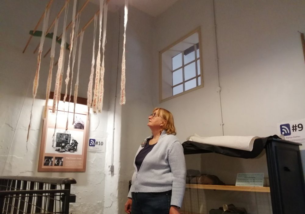 Artist Sarah Lowe looking at a Lives Unravelled installation