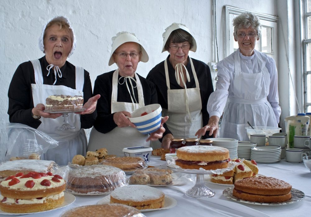 Volunteers in Victorian costume baking cakes