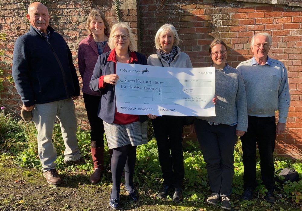 A group of people in the garden holding a giant cheque
