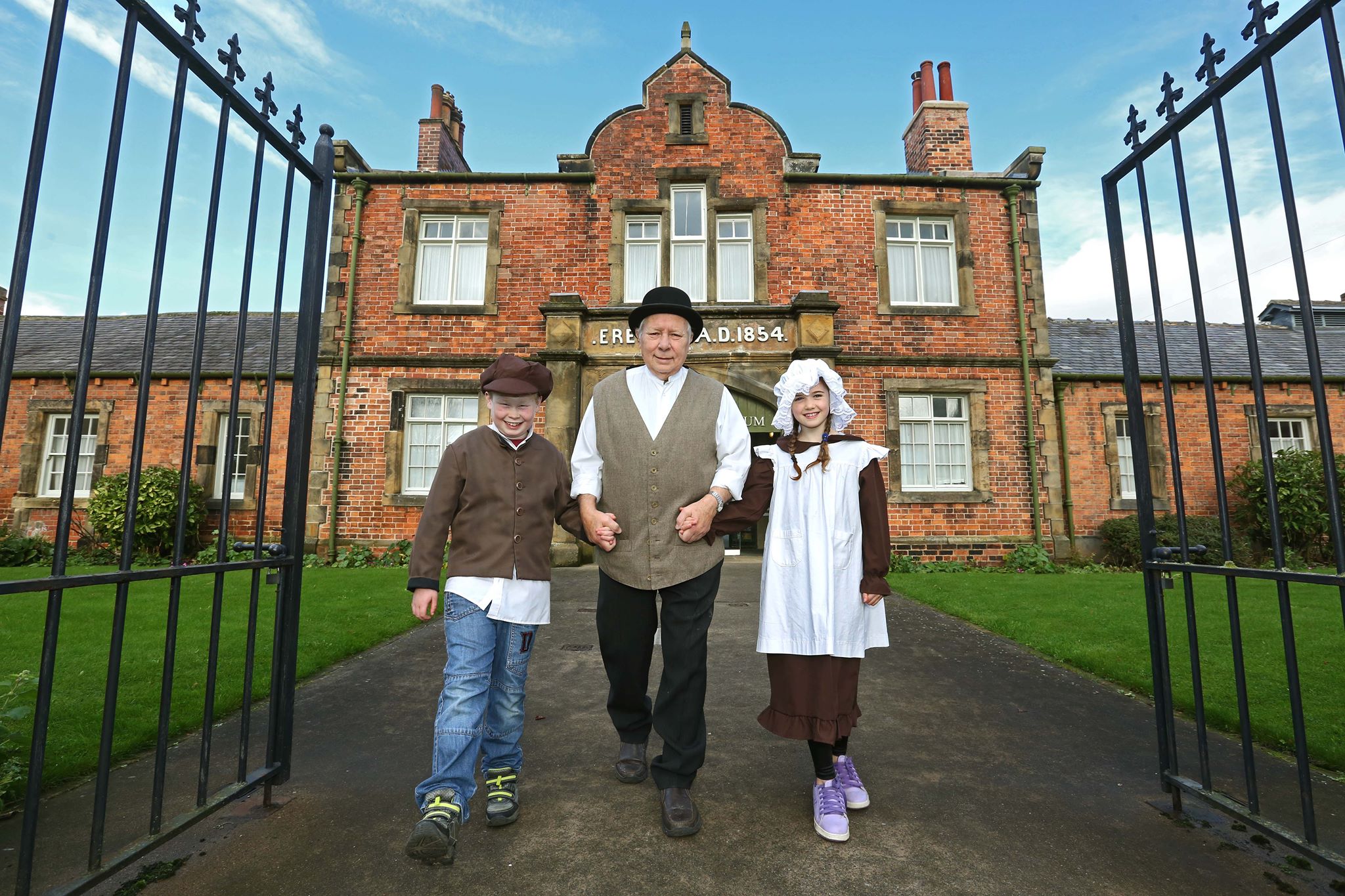 A man in Victorian costume with two children outside the Workhouse Museum