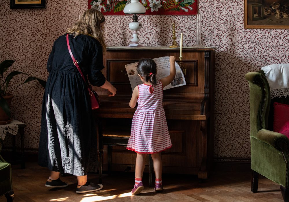 Little girl and her mum looking at a piano