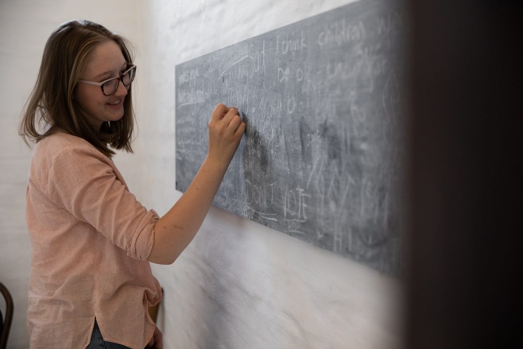 A young woman writing on a blackboard