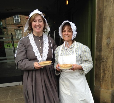 Two women in Victorian dress holding wilfra cakes