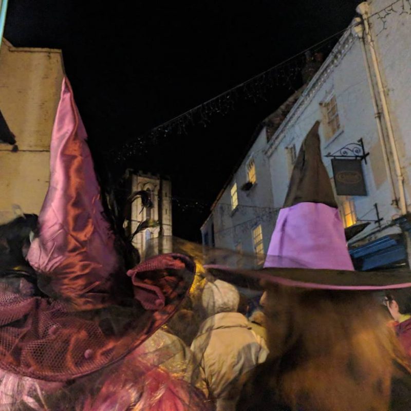 Lots of Halloween witches hats walking down a cobbled street.