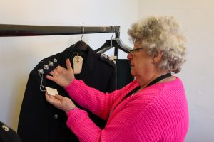 Collections and conservations manager inspects a police uniform from the collection at Ripon Museums