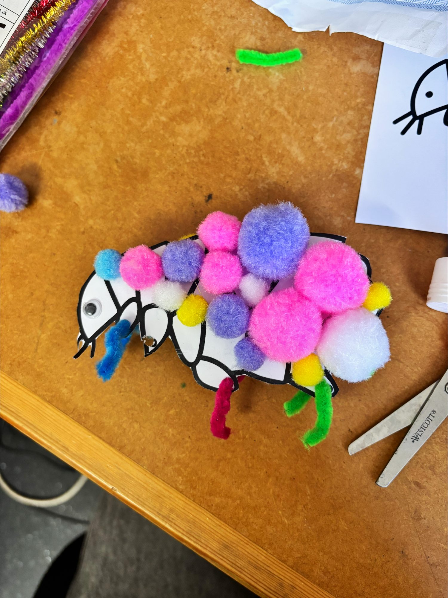 An arts and crafts flea made of pom poms and pipe cleaners